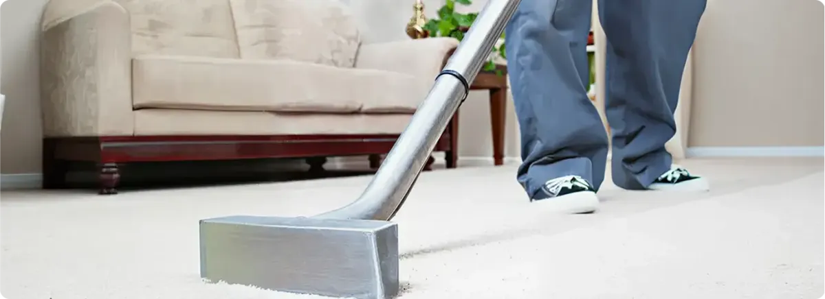 Carpet cleaning technician using a hot-water extraction wand on a light-colored carpet in a living room, Akron, OH.