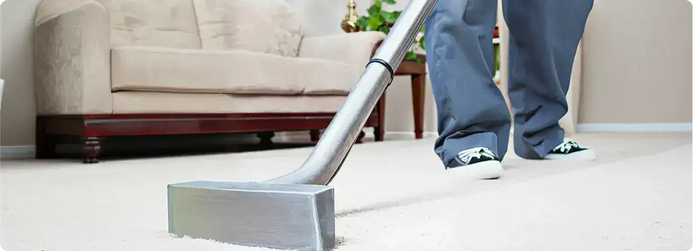 Carpet cleaning technician using a hot-water extraction wand on a light-colored carpet in a living room, Akron, OH.