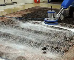 Professional rug cleaning with a rotary floor machine and shampoo foam, deep-cleaning an area rug, in Akron, OH.