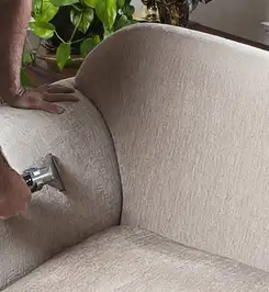 Professional upholstery cleaner deep-cleaning a fabric sofa with a handheld extraction tool and hose Akron, OH.